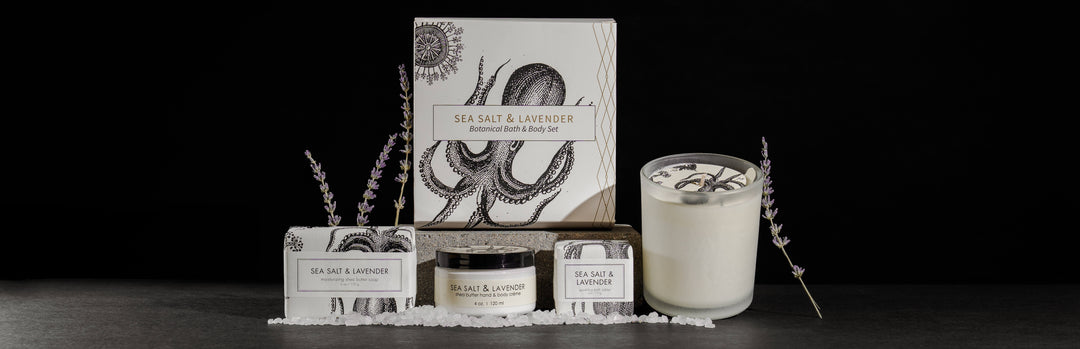 Sea salt and lavender-themed bath products set against a dark backdrop. Includes a boxed set, candle, body scrub, and soap, accented with lavender sprigs and sea salt. Packaging features an octopus illustration.