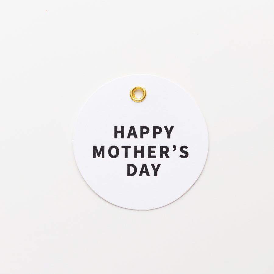 A round white tag with a small gold hole at the top center features the text "HAPPY MOTHER'S DAY" in bold, black letters in the middle. The background is plain white.